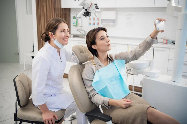 Una giovane donna che si fa un selfie con il dentista — Foto Stock
