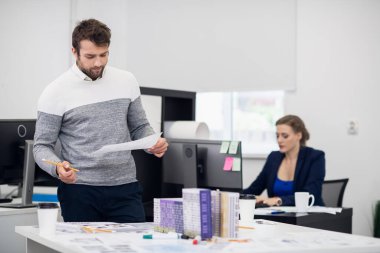 Ofis rutini. İki ofis yöneticisi, bir erkek ve bir kadın, iş yerinde.