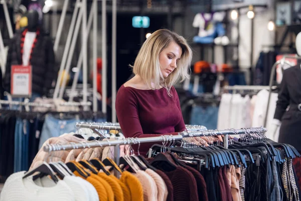 Eine junge Frau in einem Einkaufszentrum kauft Kleidung — Stockfoto