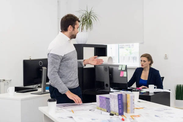 Erkek ofis çalışanı bir şey sormak için bayan meslektaşına yaklaşıyor.