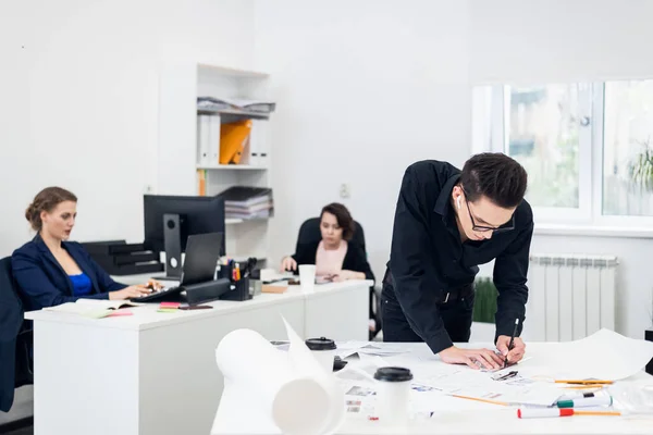 Jovem arquiteto masculino trabalhando em um projeto em um escritório espaçoso brilhante — Fotografia de Stock