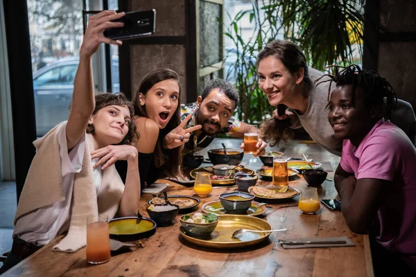 Vakantie en toerisme concept. Een multiculturele groep vrienden die selfies maken in een café tijdens een etentje — Stockfoto