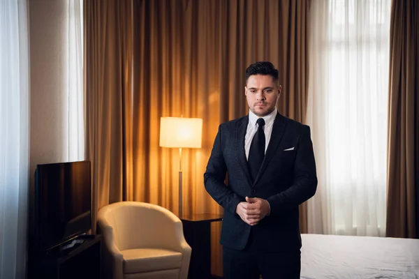 A shot of a young businessman dressing up in front of the camera, adjusting his cuffs