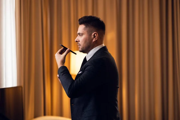 Jovem empresário falando ao telefone em seu quarto de hotel — Fotografia de Stock