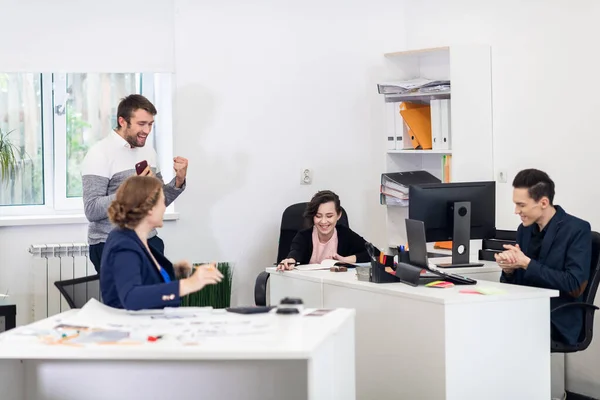 Ein glückliches Team, das gerade gute Nachrichten am Telefon erhalten hat, jubelt im Büro — Stockfoto