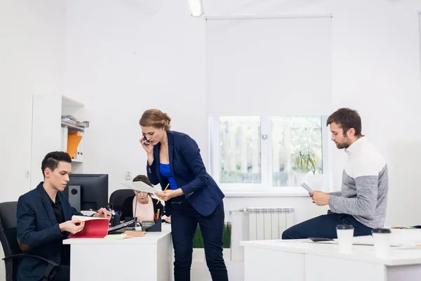 Ein geschäftiger Arbeitstag im modernen Büro. Vier Personen im Büro, jeder mit seiner eigenen Aufgabe beschäftigt — Stockfoto