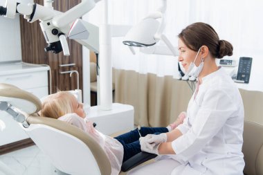 Küçük bir kızın dişlerinin klinikteki bir kadın doktor tarafından kontrol edilmesi.