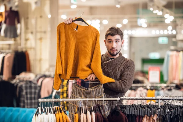 Молодой человек помогает своей девушке найти подходящий наряд в магазине одежды — стоковое фото