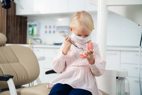 Маленькая блондинка играет дантиста в клинике — стоковое фото