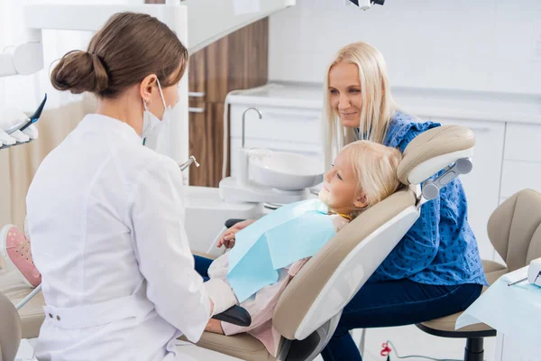Una mujer especialista en odontología pediátrica está hablando con una mujer sobre los resultados de la revisión oral de sus hijas. Oficina del dentista — Foto de Stock