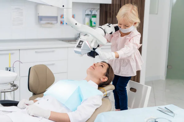 Słodka dziewczyna gra dentystę, lekarz udaje jej pacjenta — Zdjęcie stockowe
