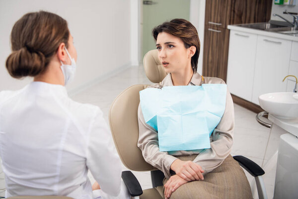 Молодая женщина, объясняющая свою зубную проблему своему доктору
