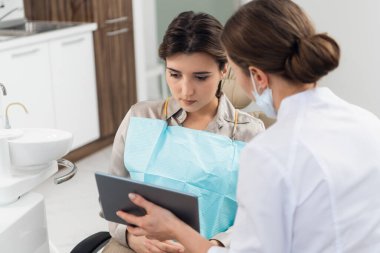 Diş kliniğinde tablet kullanan doktor olan bir kadın hasta.