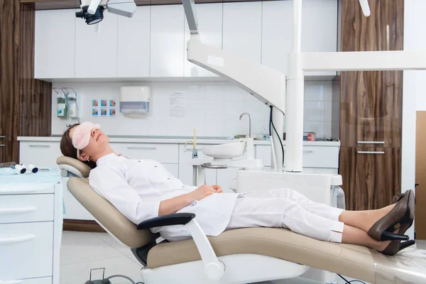 Γιατρός που κοιμάται στην οδοντιατρική καρέκλα με μάσκα ύπνου. — Φωτογραφία Αρχείου