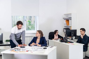 Açık bir alanda ofis çalışanları, farklı şeyler yapıyor, iş arkadaşları sohbet ediyor, projeleri tartışıyor, bilgisayarlar üzerinde çalışıyor, evrak işleriyle uğraşıyor. Eş çalışma kavramı