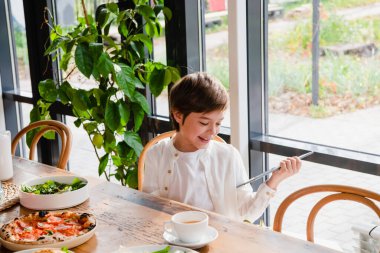 Elinde tabletle gülümseyen bir çocuk.