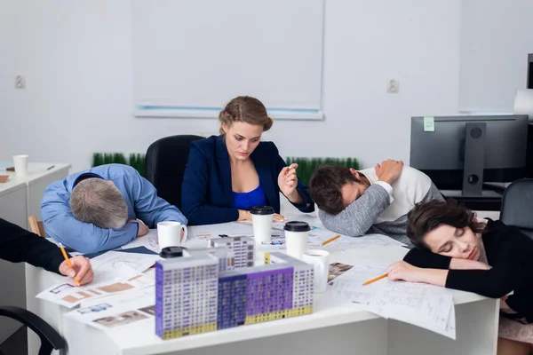 Wyczerpani pracownicy biurowi spoczywający na ich miejscu pracy, podczas gdy — Zdjęcie stockowe