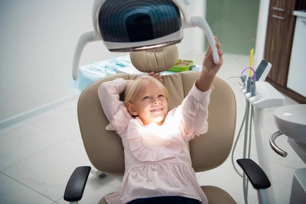 Маленькая игривая девочка сидит в кабинете дантиста — стоковое фото