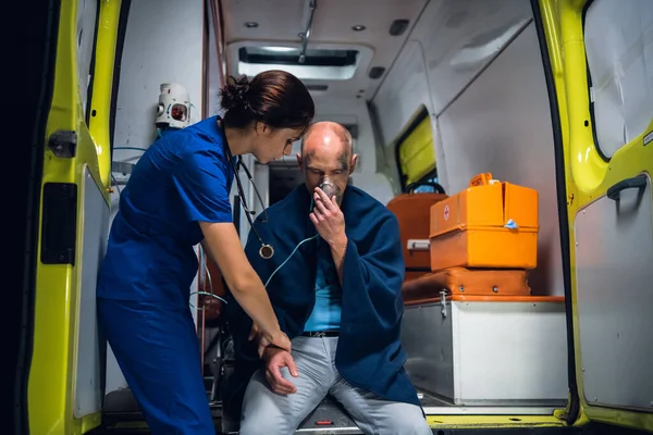 Seorang paramedis sedang memeriksa tangan seorang pria diselamatkan dari kebakaran, mungkin ada patah tulang — Stok Foto