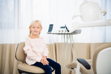 Tatmin olmuş küçük bir dişçi hasta mükemmel gülümsemesini kıç tarafında gösteriyor.