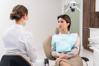 Genç bir dişçi hastasına danışıyor.