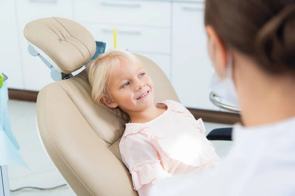 A cute little girl at the dentists office and a doctor in the f