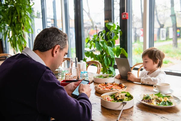 Un garçon joue sur sa tablette au bureau de la cuisine — Photo