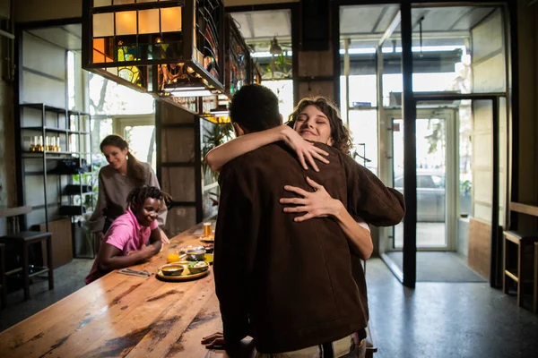 Une jeune jolie fille étreignant un garçon dans un café pour le saluer, leur — Photo