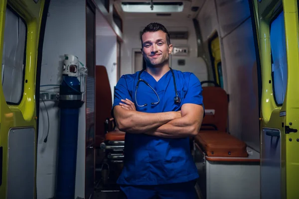 Joven médico sonriente con uniforme azul de pie y mirando a la cámara —  Fotos de Stock