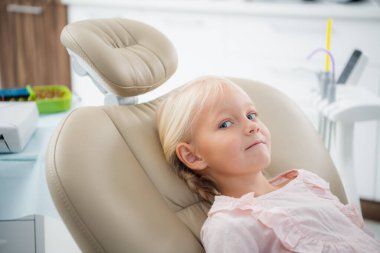 Diş muayenehanesinde bekleyen küçük bir kızın yakın çekimi.