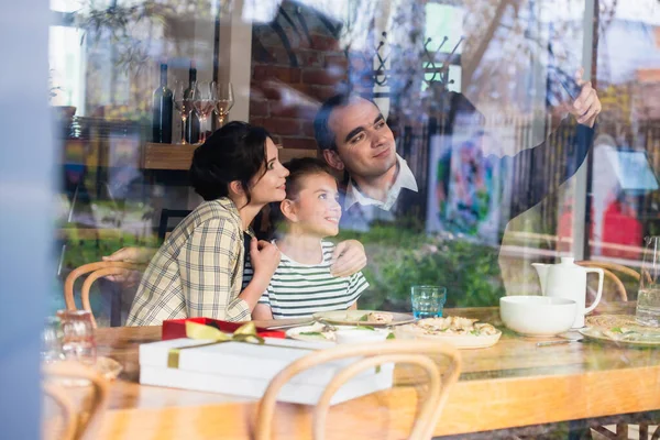 Une famille heureuse de trois personnes faisant des selfies dans un café — Photo
