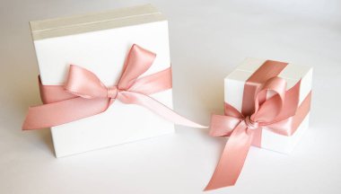 Beyaz arka planda pembe kurdeleli iki beyaz hediye kutusu. Noel ya da Sevgililer Günü Pembe kurdeleli beyaz hediye kutusu.