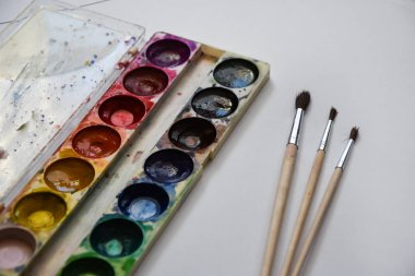 Boya, guaj ve beyaz arka planda izole edilmiş bir fırça, kopyalama alanı, metin için yer, ressamın çalışma yeri. Okul afişi