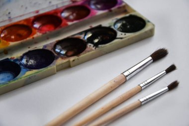 Boya, guaj ve beyaz arka planda izole edilmiş bir fırça, kopyalama alanı, metin için yer, ressamın çalışma yeri. Okul afişi