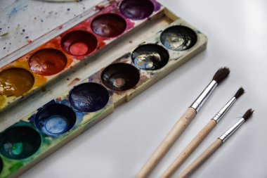 Boya, guaj ve beyaz arka planda izole edilmiş bir fırça, kopyalama alanı, metin için yer, ressamın çalışma yeri. Okul afişi