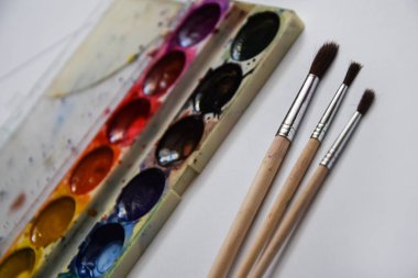 Boya, guaj ve beyaz arka planda izole edilmiş bir fırça, kopyalama alanı, metin için yer, ressamın çalışma yeri. Okul afişi