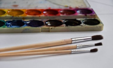 Boya, guaj ve beyaz arka planda izole edilmiş bir fırça, kopyalama alanı, metin için yer, ressamın çalışma yeri. Okul afişi