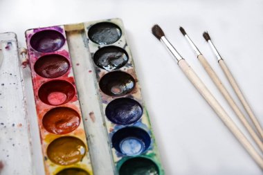 Boya, guaj ve beyaz arka planda izole edilmiş bir fırça, kopyalama alanı, metin için yer, ressamın çalışma yeri. Okul afişi