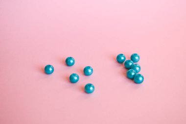 Yumuşak pembe arkaplan üzerinde parlak pembe incilerden oluşan güzel mavi bir grup.