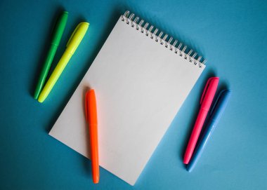 Mavi arkaplan ofis masası ve farklı nesnelerin boş kağıt sayfasının üst görünümü. Minimum düz yatay biçim kopyalama alanı, dizüstü bilgisayar 