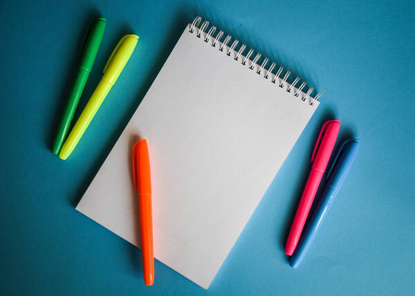 Top view of blank paper page on blue background office desk and different objects. Minimal flat lay style copy space, notebook 