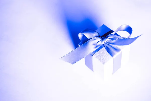 white present boxes with blue ribbon on the classic blue pantone background. christmas or valentines day white gift box