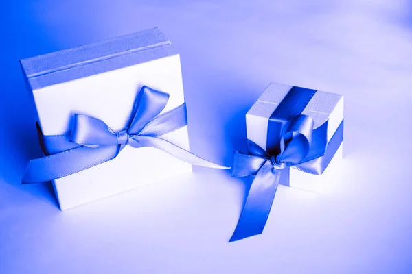 white present boxes with blue ribbon on the classic blue pantone background. christmas or valentines day white gift box