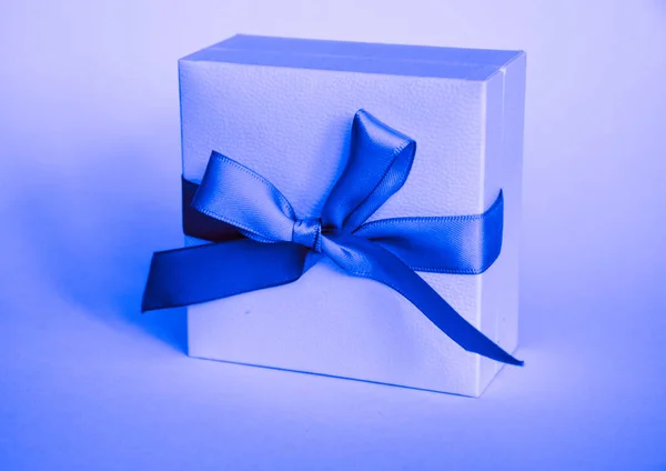 white present boxes with blue ribbon on the classic blue pantone background. christmas or valentines day white gift box