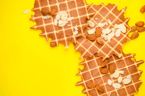 Waffles caseiros com nozes de amêndoa e flocos de amêndoa no fundo amarelo, vista superior, espaço de cópia — Fotografia de Stock