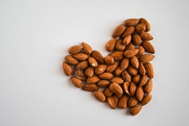 Beyaz arka planda kalp şeklinde badem fıstıkları, düz yatış, fotokopi alanı, sağlıklı beslenme 
