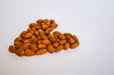 Beyaz arka planda kalp şeklinde badem fıstıkları, düz yatış, fotokopi alanı, sağlıklı beslenme 