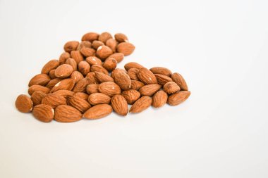 Beyaz arka planda kalp şeklinde badem fıstıkları, düz yatış, fotokopi alanı, sağlıklı beslenme 