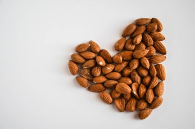Beyaz arka planda kalp şeklinde badem fıstıkları, düz yatış, fotokopi alanı, sağlıklı beslenme 
