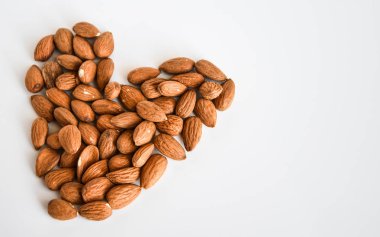 Beyaz arka planda kalp şeklinde badem fıstıkları, düz yatış, fotokopi alanı, sağlıklı beslenme 